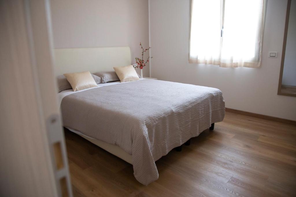 1 dormitorio con 1 cama blanca y suelo de madera en B&B STELLANOVA en San Donnino della Nizzola
