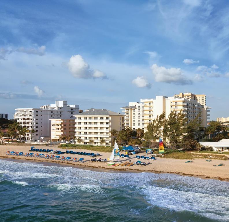 a beach with chairs and beach umbrellas and buildings at Club Wyndham Royal Vista in Pompano Beach