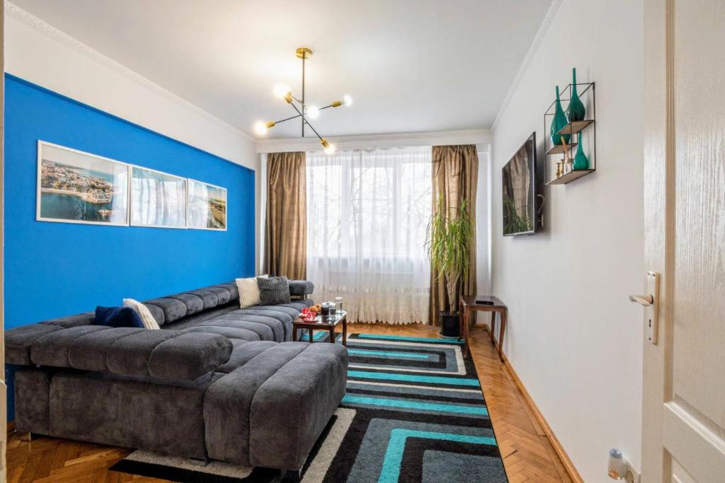 Modern & Stylish Apartment Excellent Location Superhost في كونستانتا: غرفة معيشة مع أريكة والجدار الأزرق