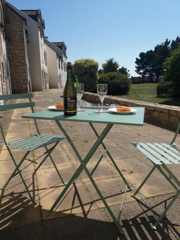 Una botella de vino sentada en una mesa con dos sillas en Ker Lomic, en Arzon