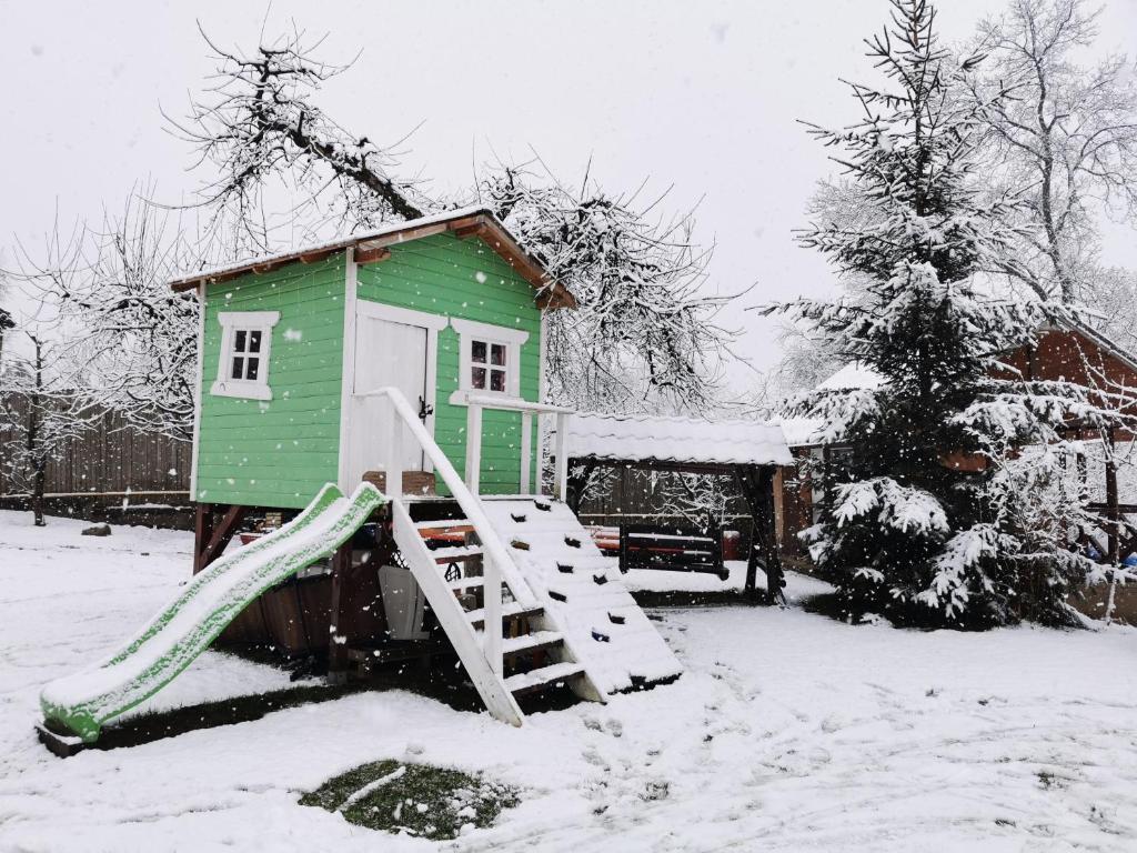 ein grünes Haus mit einer Rutsche im Schnee in der Unterkunft Casa Bunicii Comarnic in Comarnic