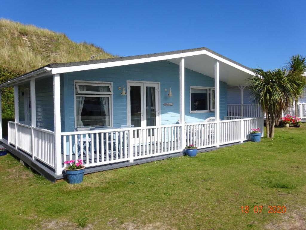 a blue manufactured home with a porch and white railing at Bryn Banc in Gwithian