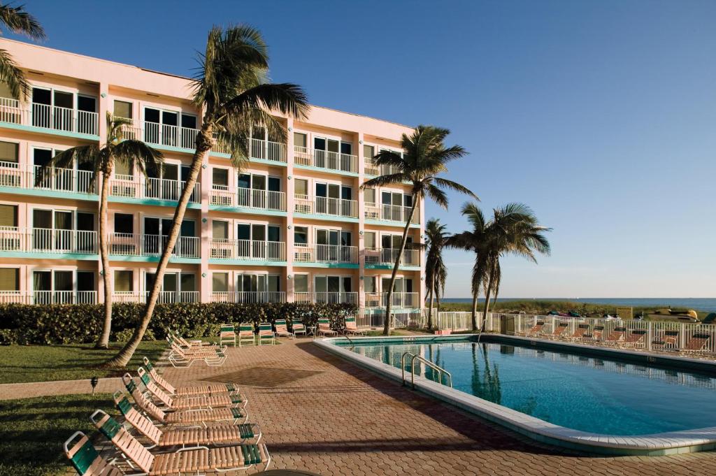 a large hotel with a swimming pool and palm trees at Club Wyndham Sea Gardens in Pompano Beach