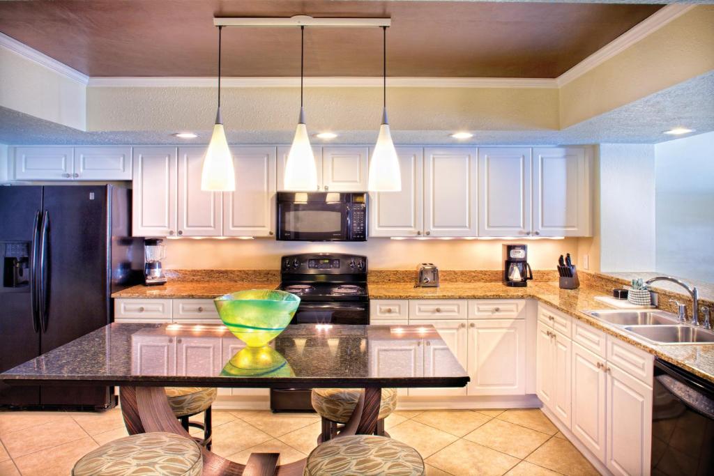 a kitchen with white cabinets and a black counter top at Club Wyndham Panama City Beach in Panama City Beach