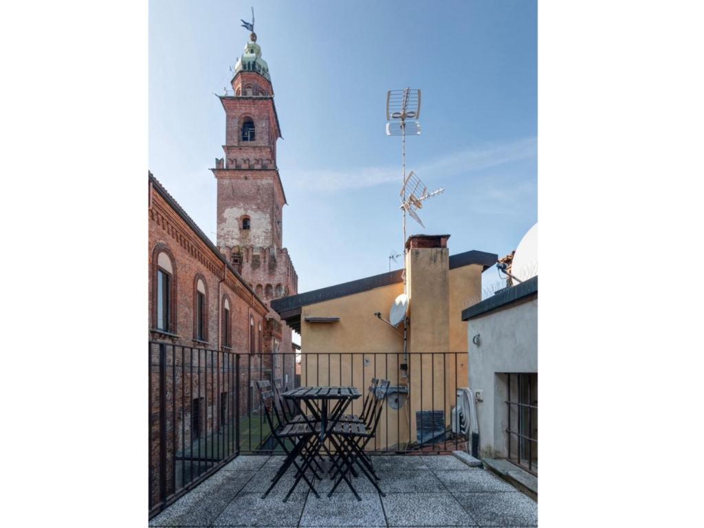 a balcony with a table and a clock tower at Bea Ducale in Vigevano