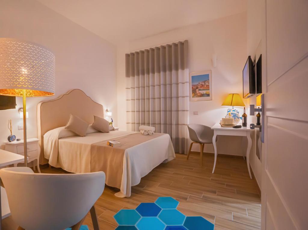 Cette chambre comprend un lit et un bureau. dans l'établissement La Serenata Luxury, à Maiori