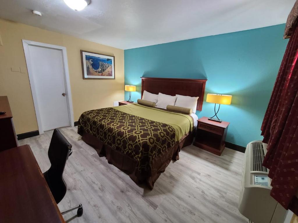 a hotel room with a bed and a blue wall at America's Value Inn in Tulsa