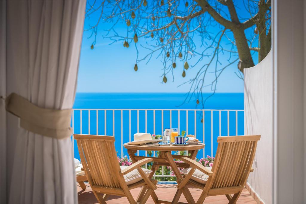 een tafel en stoelen op een balkon met uitzicht op de oceaan bij Villa Fortuna in Positano