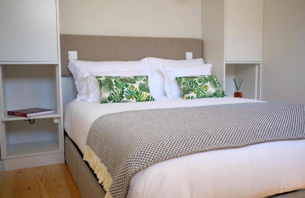 een slaapkamer met een groot wit bed met kussens bij Adega Floresta Residence in Porto