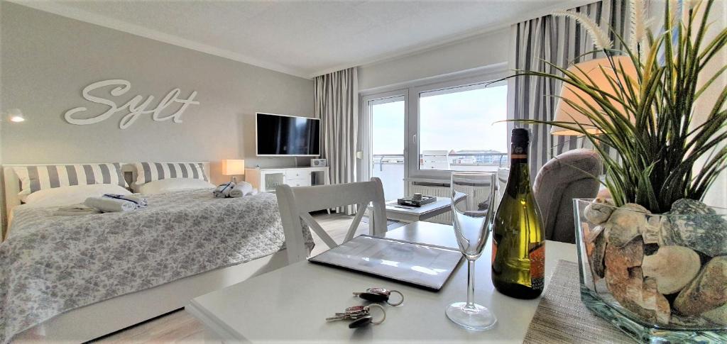 a bedroom with a bed and a table with a bottle of wine at Haus Nordland Wg. 109 in Westerland