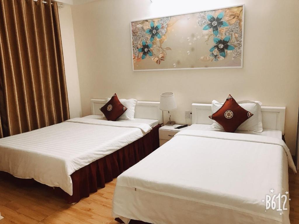 duas camas num quarto de hotel com um quadro na parede em Dragon hotel em Ha Long