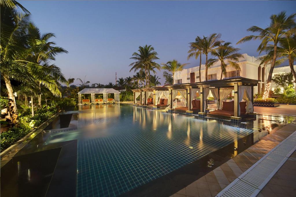 una piscina di fronte a una casa con palme di Mayfair Palm Beach Resort a Gopālpur