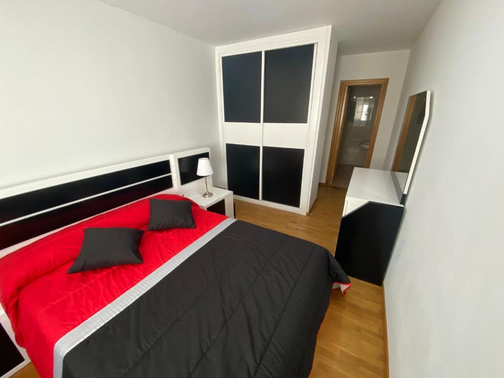 um quarto com uma cama vermelha e preta num quarto em Piso céntrico, con amplia terraza, 3 dormitorios em Ribeira