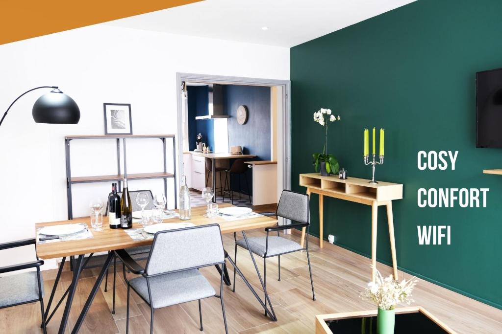 a dining room with a table and chairs and a green wall at Le Grand Chambord 2 in Laval