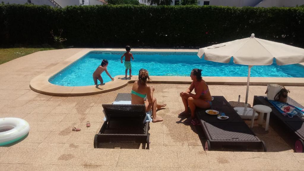 a group of people sitting around a swimming pool at Villa Sirena in Cala en Blanes