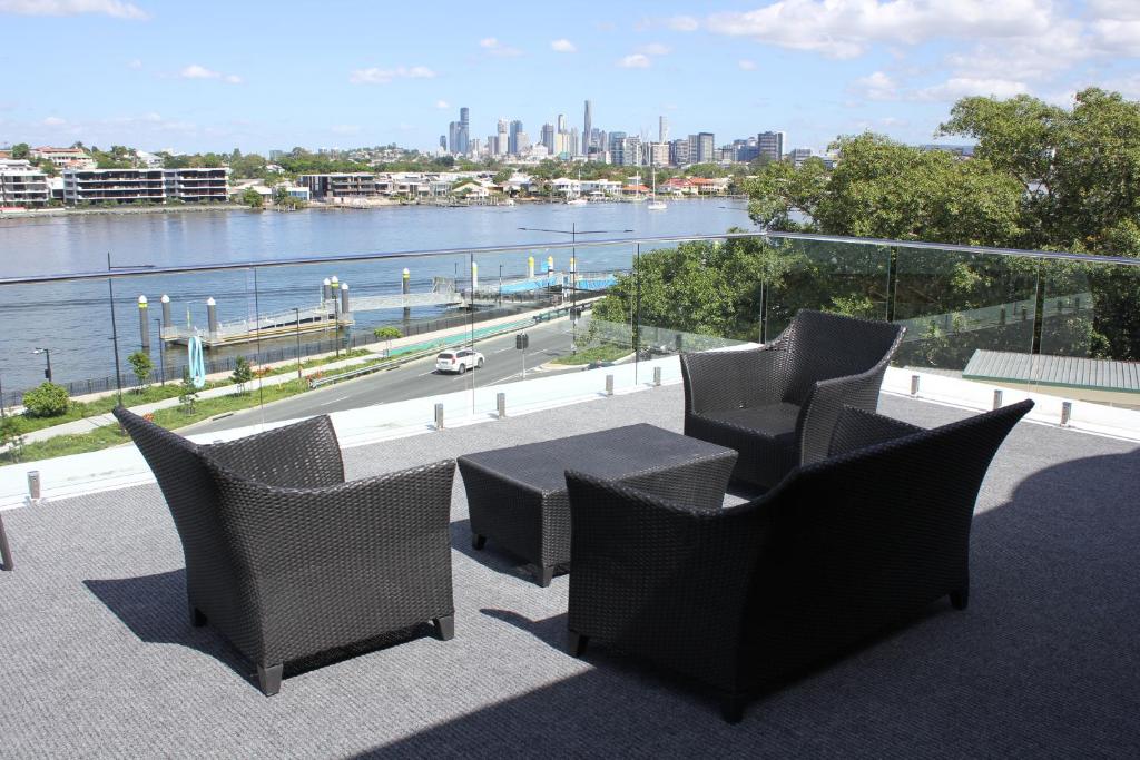 a balcony with chairs and a table and a river at Hamilton Motor Inn in Brisbane