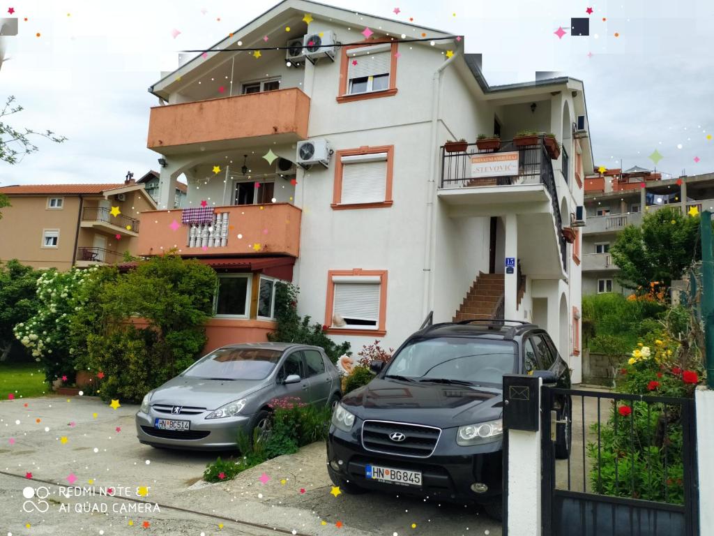 dwa samochody zaparkowane przed domem w obiekcie Apartments Stevović w mieście Herceg Novi