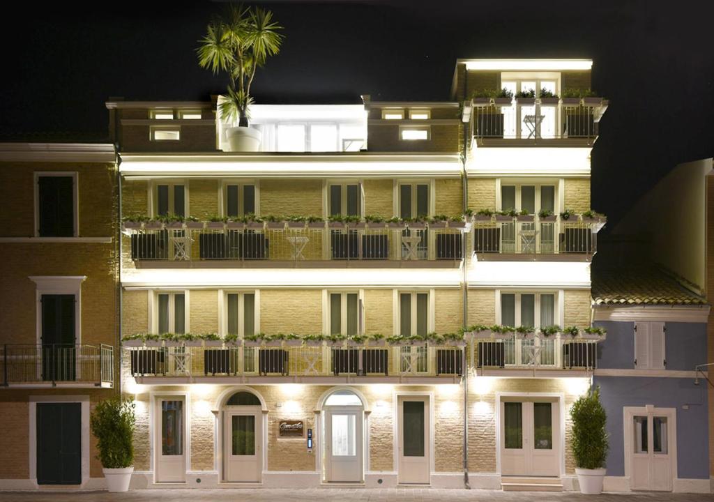 a large yellow building with plants on the balconies at night at Opera Arte Suite Apartments in Porto Recanati