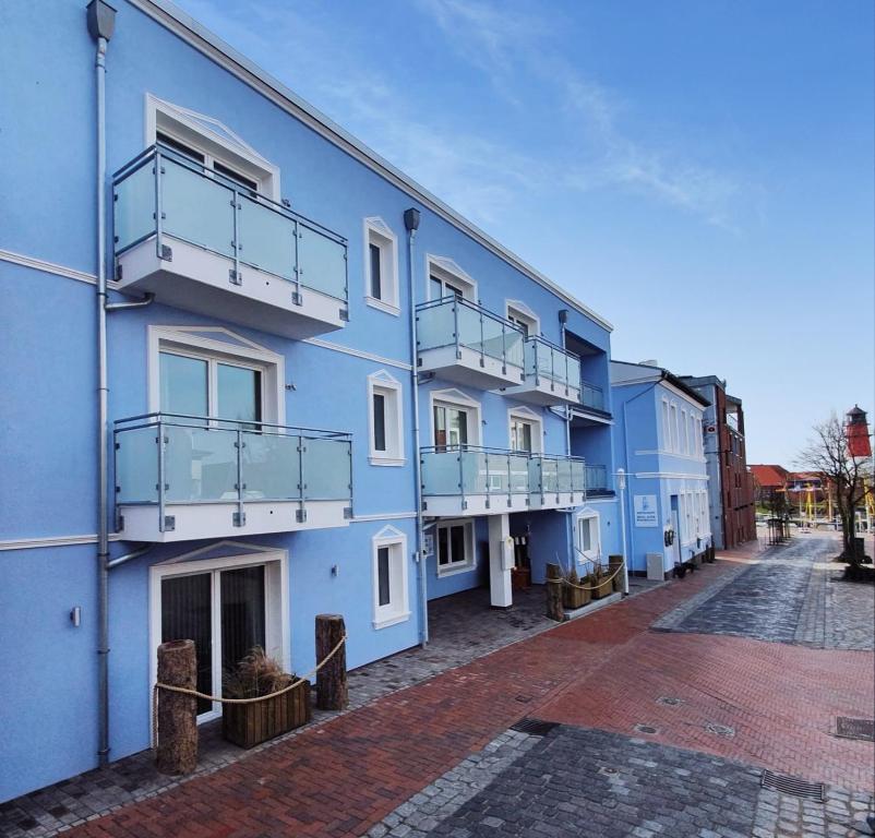 un edificio azul con balcones en una calle en Hotel Alter Muschelsaal en Büsum