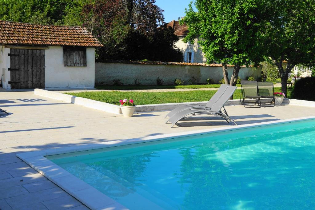 a swimming pool with two lounge chairs next to a house at Le Chemin in Challignac