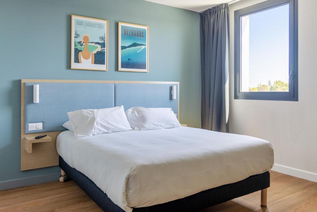 um quarto com uma cama grande num quarto com uma janela em Kyriad Bordeaux Nord Sainte Eulalie em Sainte-Eulalie