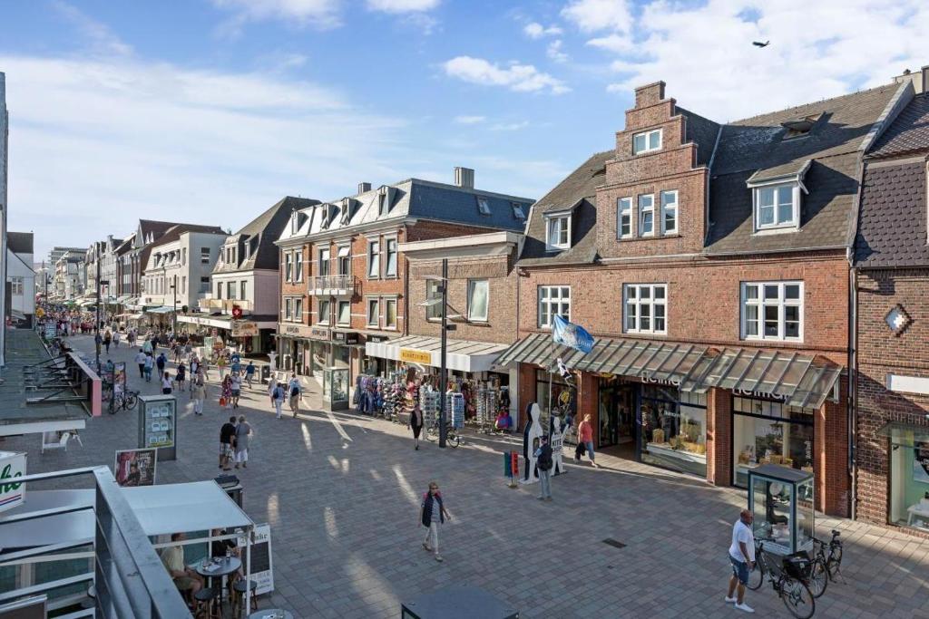 un groupe de personnes marchant dans une rue avec des bâtiments dans l'établissement Die-Schlosserei-Luxus-in-der-Friedrichstrasse, à Westerland