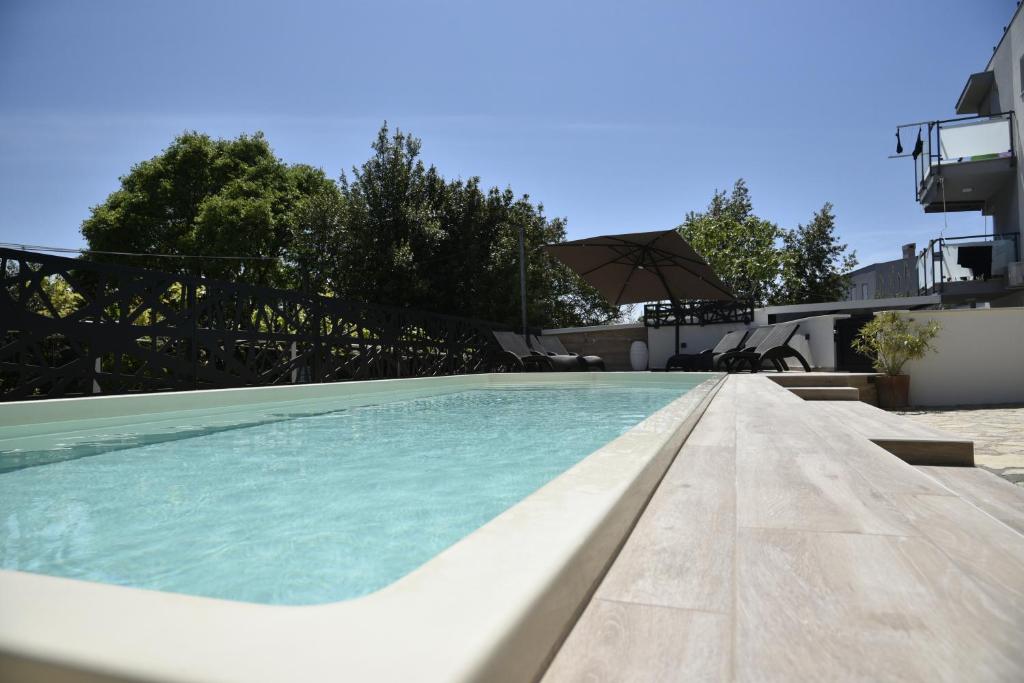 una piscina con sombrilla junto a una casa en Apartment Lounge en Pula
