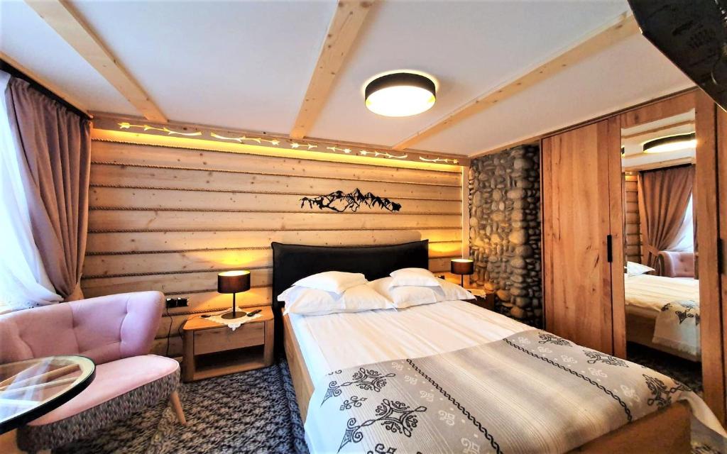 ムジャシフレにあるECO Villa Karpatia Ski&SPAのベッドルーム1室(ベッド1台、椅子、テーブル付)