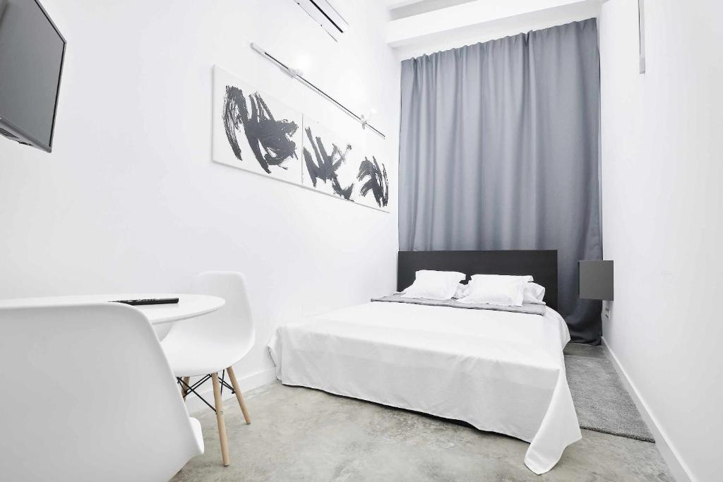 a white bedroom with a white bed and a desk at FERIA MODERN y LUXURY in Seville