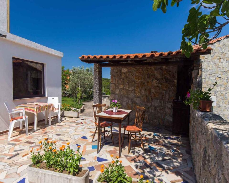 a patio with a table and chairs and a stone wall at Apartment in Vrbnik/Island Krk 35842 in Vrbnik