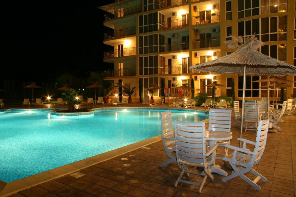 a table with an umbrella and chairs next to a swimming pool at Joya Park Apartments in Golden Sands