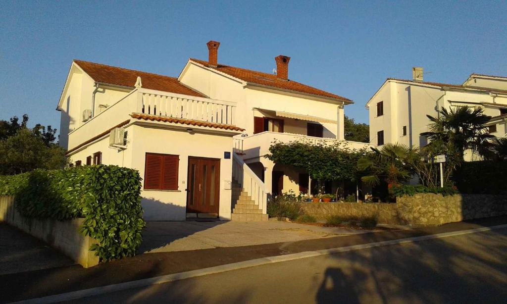 una grande casa bianca con un cancello davanti di Apartments in Njivice/Insel Krk 34038 a Njivice