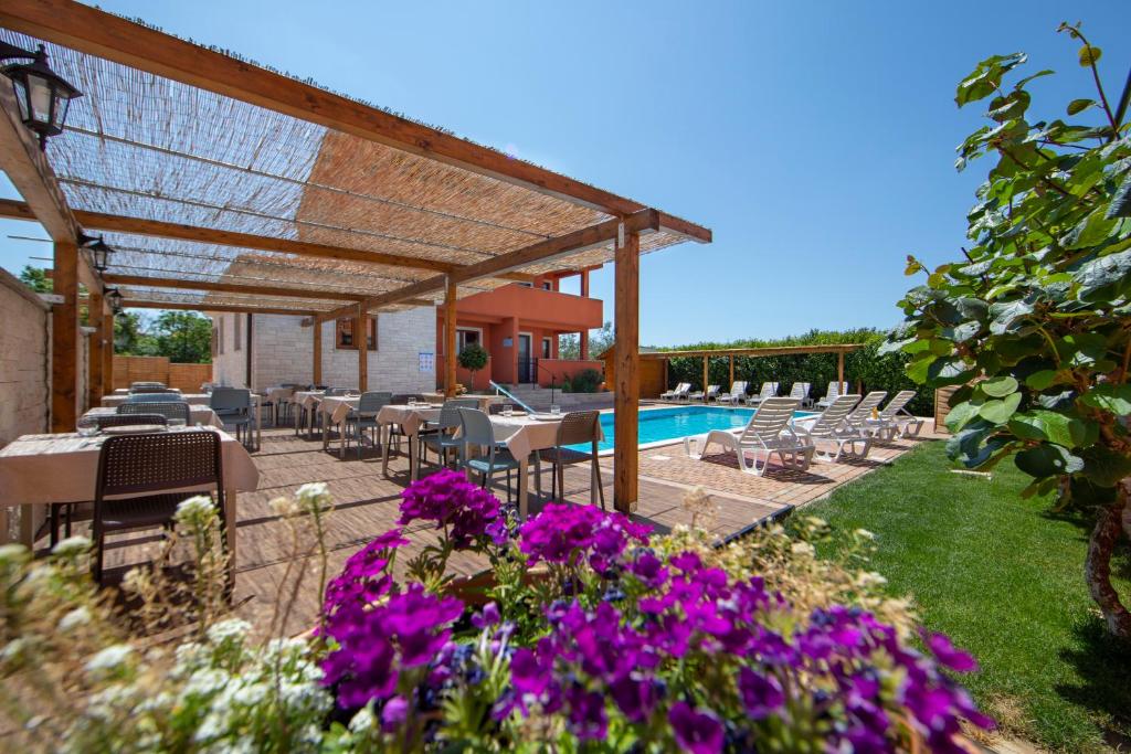 eine Terrasse mit Tischen, Stühlen und lila Blumen in der Unterkunft Hotel Natura Vilanija in Umag