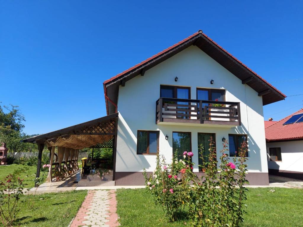 a white house with a balcony and a yard at Pensiunea Maria in Polovragi