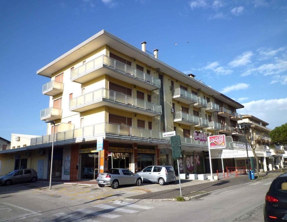 ein großes Gebäude mit davor geparkt in der Unterkunft Apartments in Eraclea Mare 25611 in Eraclea Mare