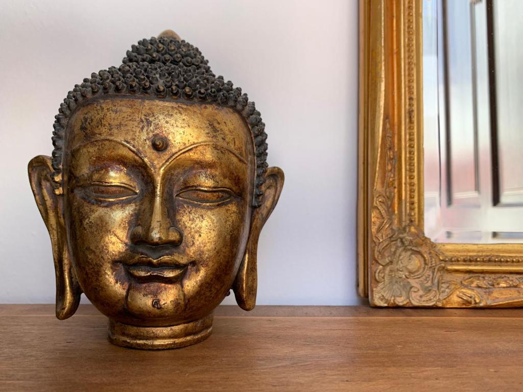 eine goldene Statue auf einem Tisch neben einem Spiegel in der Unterkunft Pequeño Paraíso Lanzarote, modernes Ferienhaus am Meer für 4 in Playa Honda