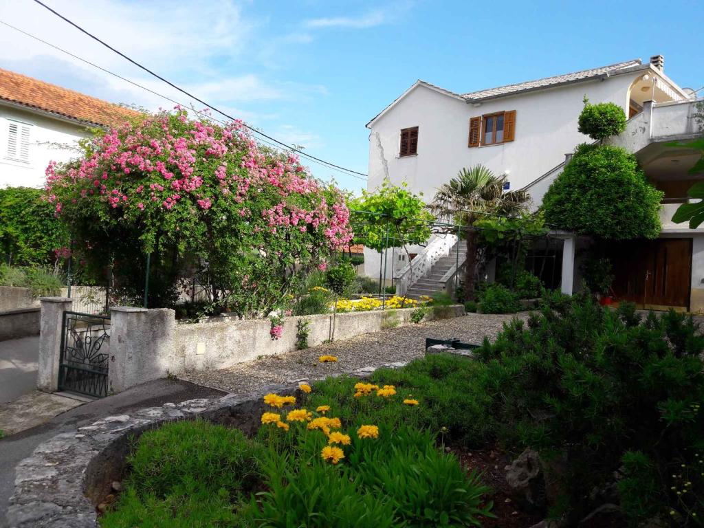 un jardin avec des fleurs roses et jaunes devant une maison dans l'établissement Dobrinj Apartment 2, à Dobrinj