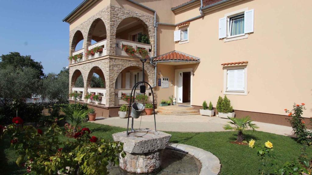 a large house with a fountain in the yard at Malinska Apartment 1 in Sveti Anton