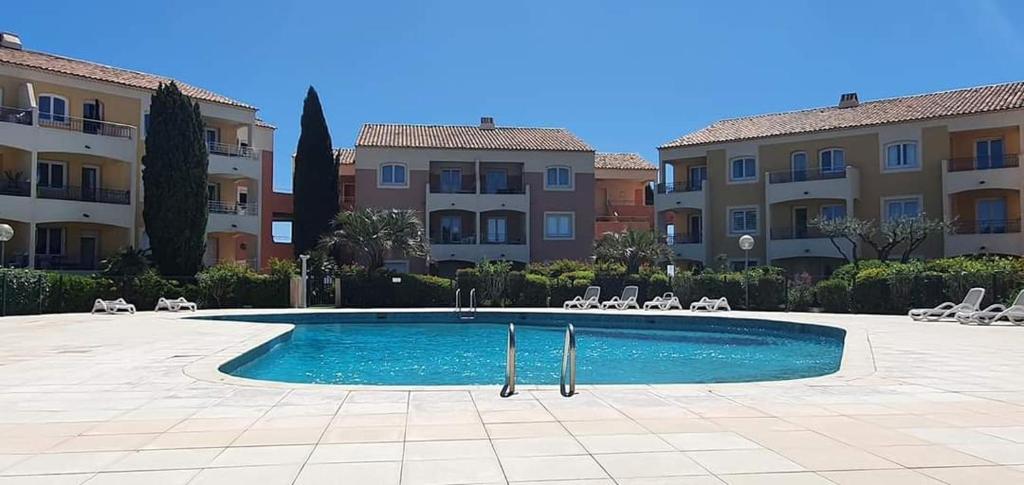 uma piscina em frente a alguns edifícios em Vacance location mer piscine var sud terrasse em Les Issambres