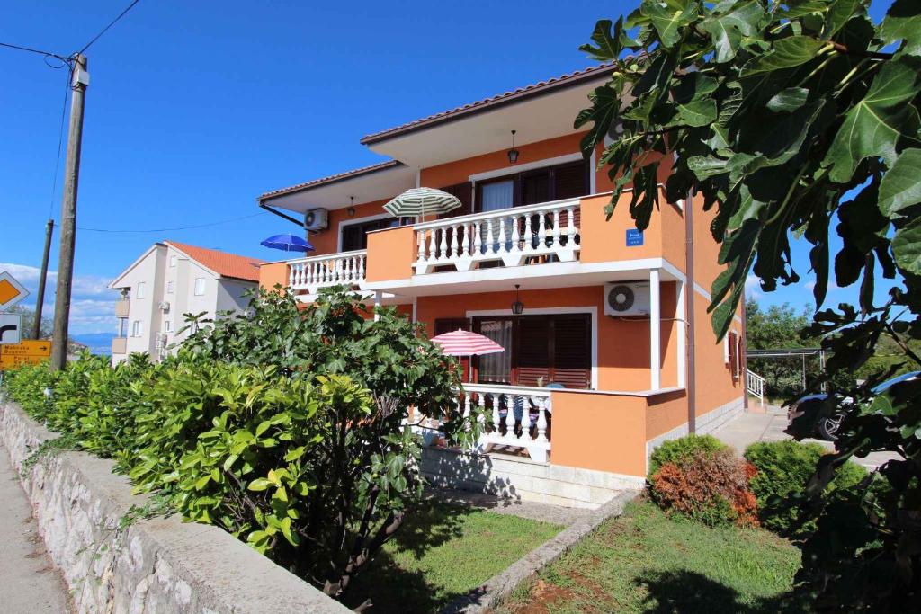 a orange house with a balcony on a street at Apartment Malinska, Krk 19 in Malinska