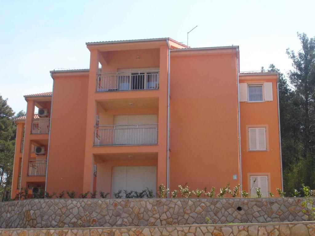 ein orangefarbenes Gebäude mit Balkonen und einer Steinmauer in der Unterkunft Apartment Soline 2 in Soline