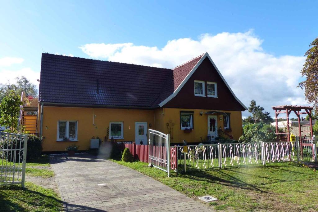 una casa gialla e rossa con una recinzione bianca di Apartment Fuhlendorf 1 a Bodstedt