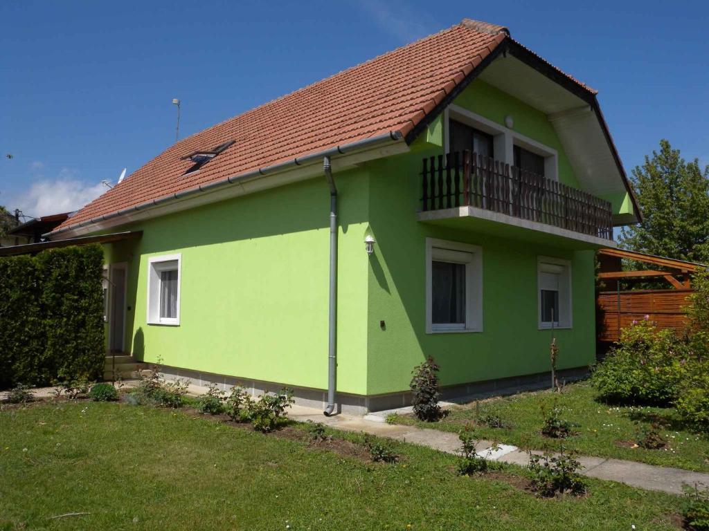 een groen en geel huis met een balkon bij Apartment Gyenesdias 3 in Gyenesdiás