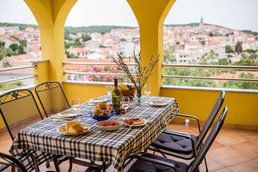 uma mesa com comida e bebidas e vista para a cidade em Apartment Vrbnik 1 em Vrbnik