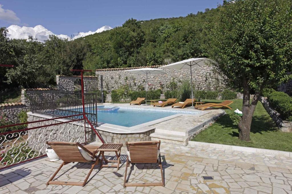 a swimming pool with two chairs and a table at Holiday home Ledenice 2 in Ledenice