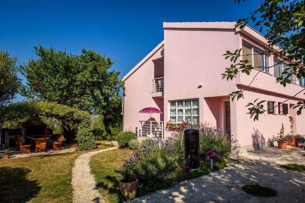 ein rosa Haus mit einem Garten davor in der Unterkunft Apartment Kozino 1O in Kožino