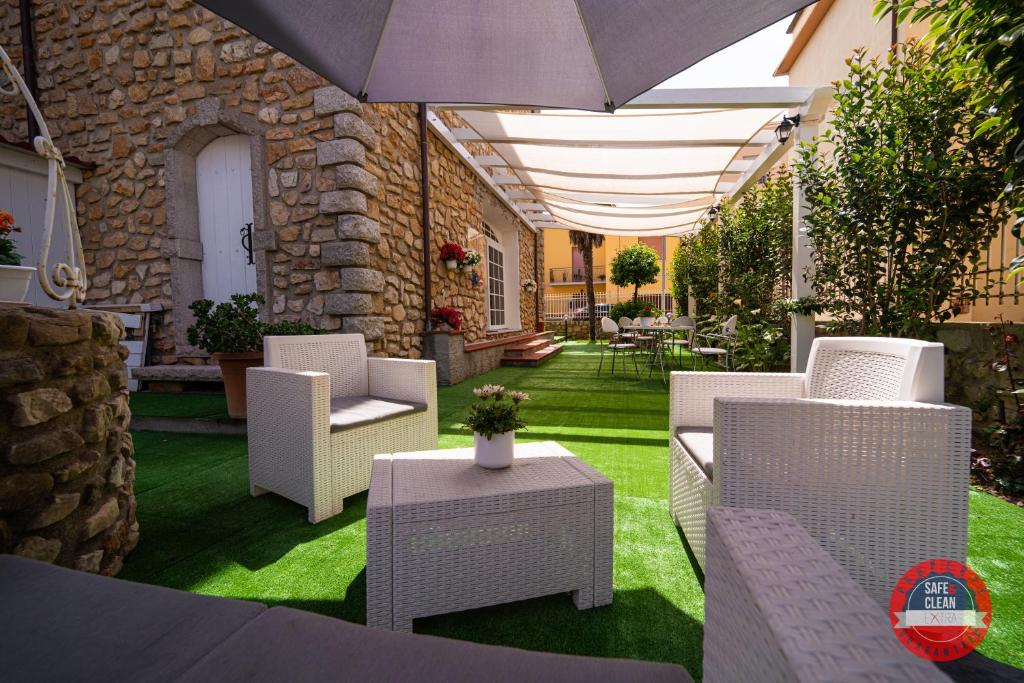 un patio con sillas blancas y una sombrilla en Villa Vittoria, en Sorso