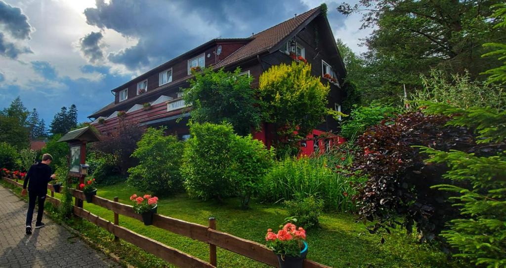 a man walking past a house with flowers in front of it at Wald-Landhaus in Hahnenklee-Bockswiese