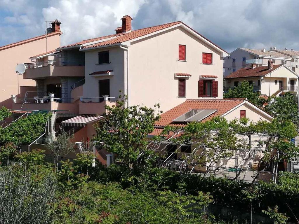 een groot wit huis met rode ramen en bomen bij Apartment Fazana 15 in Fažana