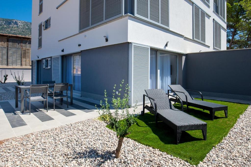 a patio with two benches and a table and chairs at Apartments Dva Galeba in Bol